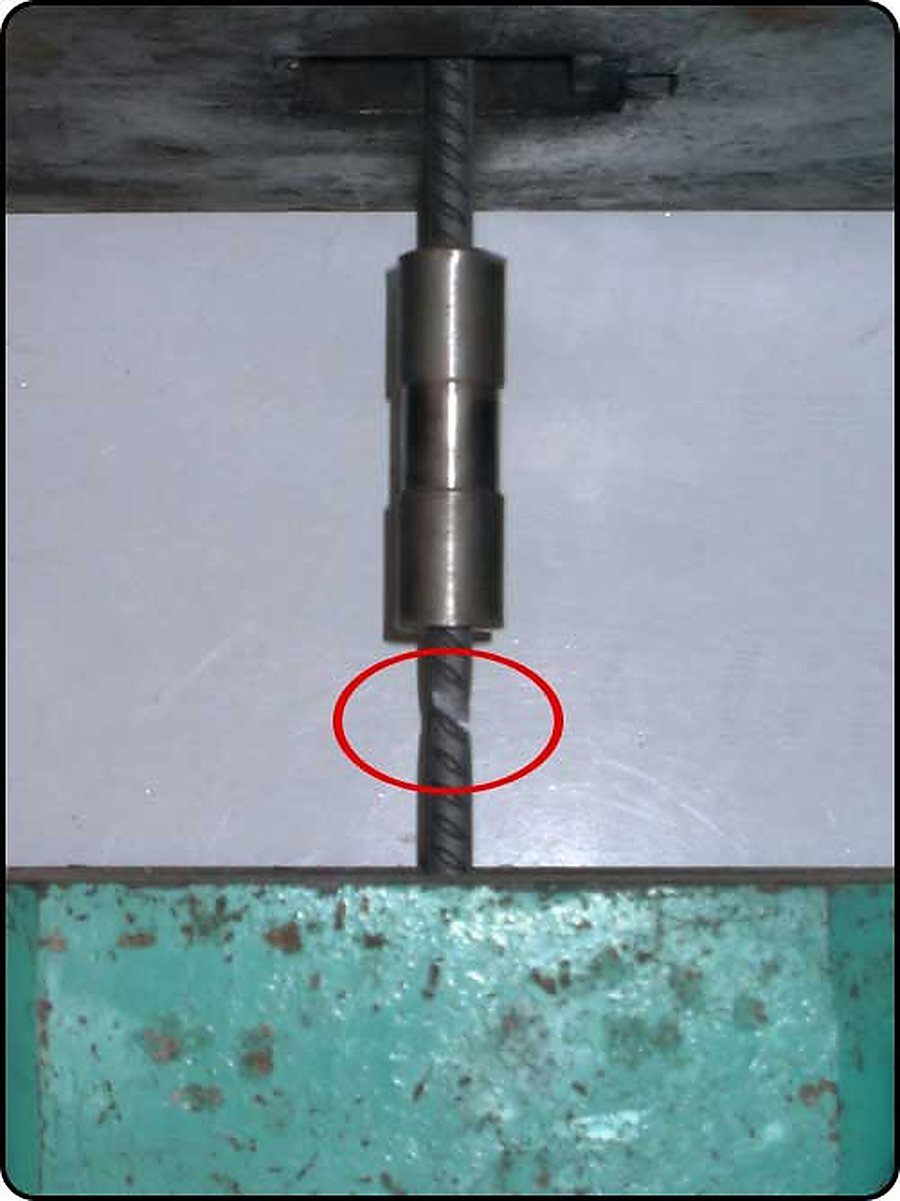 A coupler mounted on a bar in the testing machine, with the failure point on the bar circled below the sleeve.